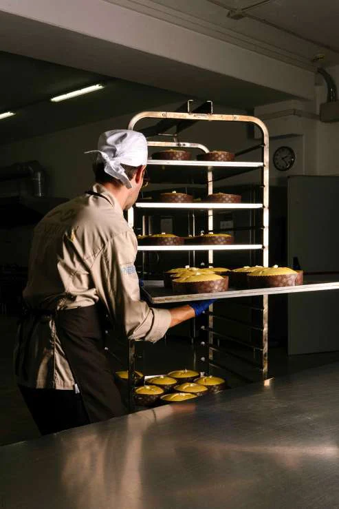 Un pasticcere sistema i panettoni sul carrello del forno